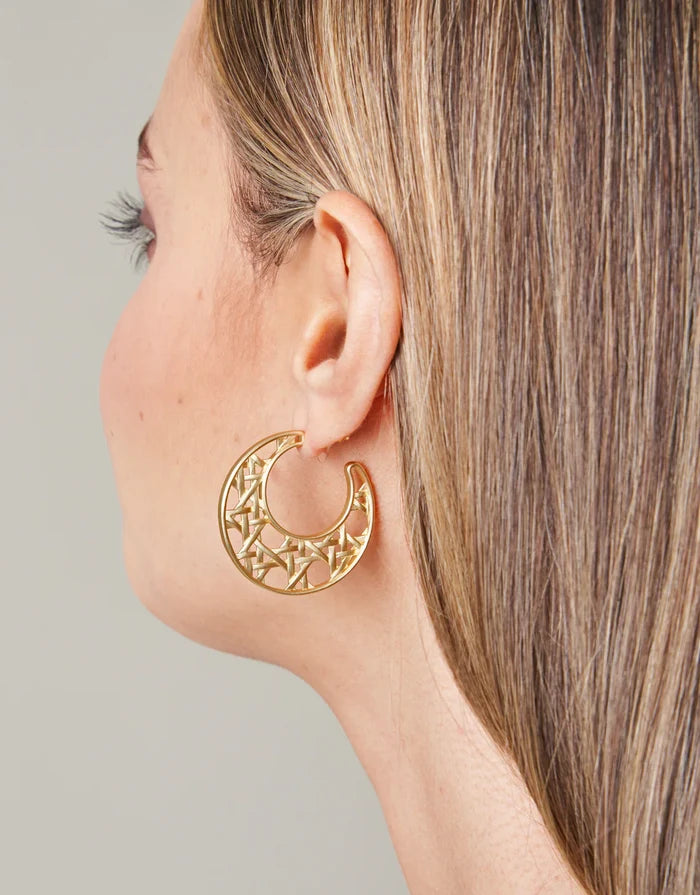 Gold hoop earring worn by a person with a neutral background