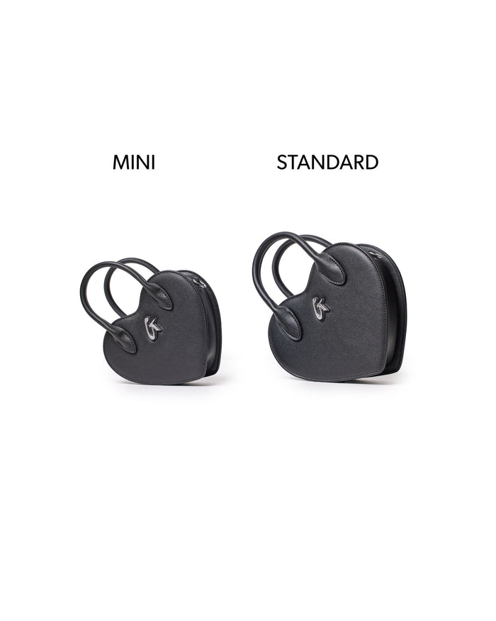 Mini black heart-shaped handbag displayed alongside a standard size version, showcasing its compact design.