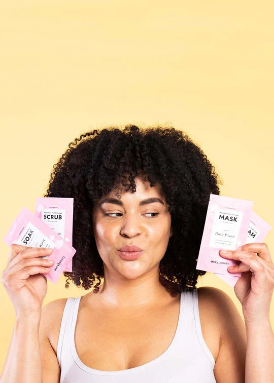 person holding up four steps of pedi kit against yellow background