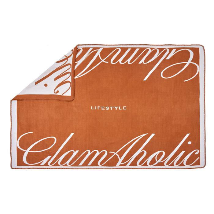 Brown luxury throw blanket with white script text, featuring "Lifestyle" and "GlamAholic" branding, folded at corner.