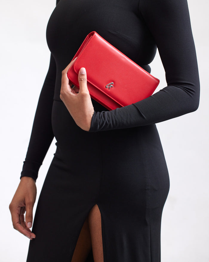 Elegant red wallet on a woman’s hand, showcasing a sleek design with a silver logo, perfect for stylish outings.
