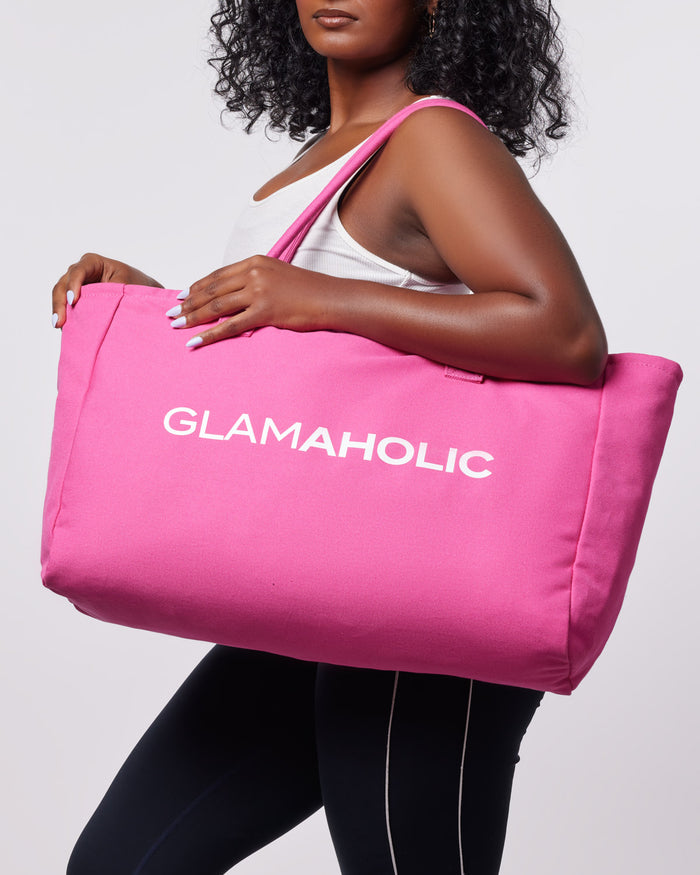 Hot pink athletic canvas tote bag held by a model, featuring the Glam-Aholic logo prominently displayed.