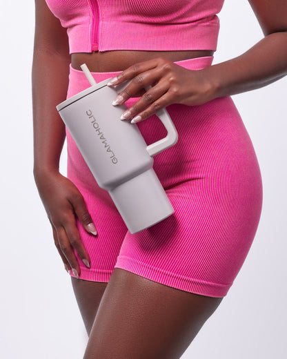 Athletic tumbler in nude held by a model wearing a pink ribbed two-piece outfit, showcasing a stylish and functional design.