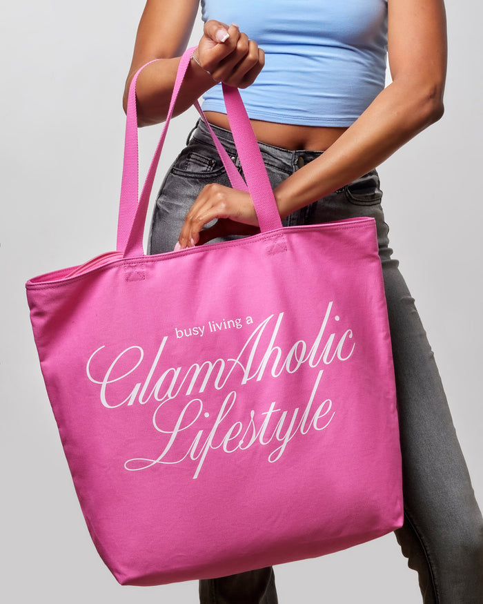 Hot pink canvas tote bag with "busy living a GlamAholic Lifestyle" printed in white, perfect for stylish everyday use.