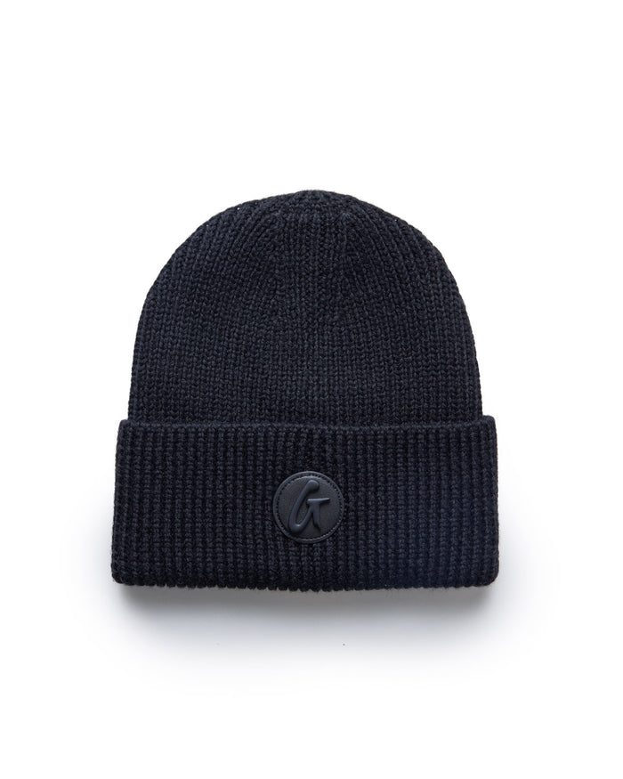 Black classic beanie hat with a folded brim and a small circular logo patch on the front.