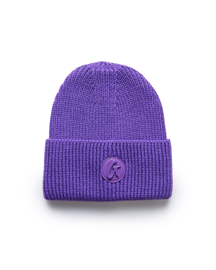 Purple classic beanie with a folded cuff and a round logo patch on the front, made of knitted fabric for warmth and style.