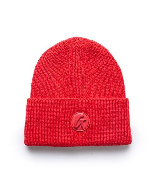 Red knit beanie with a folded cuff and a circular logo patch featuring a stylized "G" on the front.