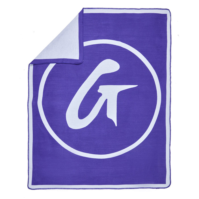 Purple classic throw blanket with a large white circular logo and stylized "G" design, folded at one corner.