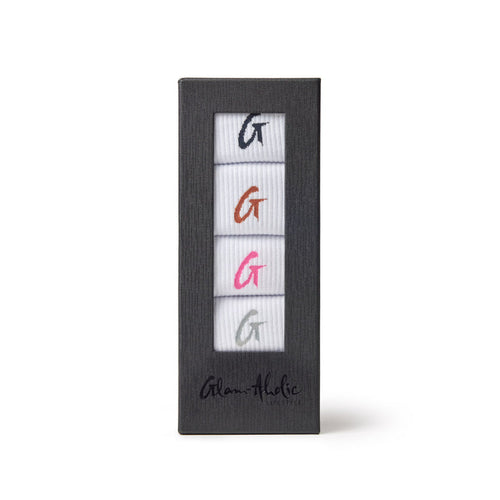 Set of four crew socks in white with colorful embroidered "G" logos in black, orange, pink, and gray, packaged in a black box.