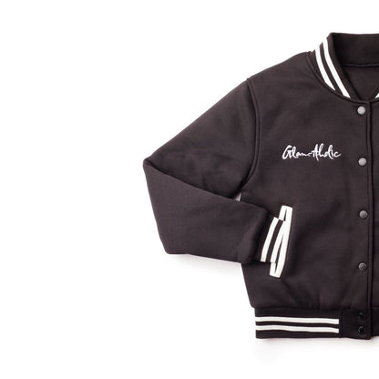 Black varsity jacket with striped cuffs, collar, and waistband, featuring embroidered "Glam-Holic" on the chest.