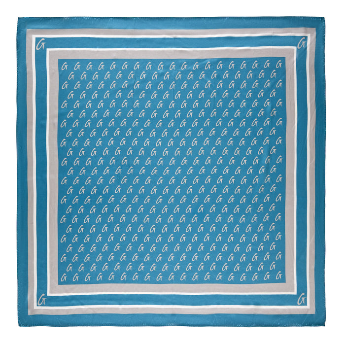 Large blue silk scarf with silver monogram pattern, featuring repeated "G" initials and border accents.