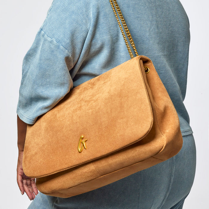 Large tan suede flap bag with a gold chain strap, showcasing a stylish and luxurious design for everyday use.