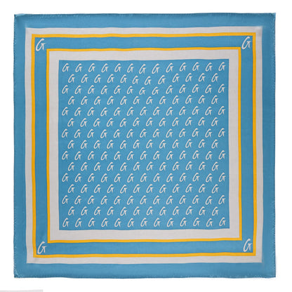 Medium blue silk scarf with a gold monogram pattern and border, featuring white "G" initials on a stylish design.