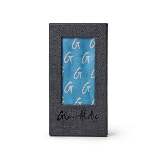 Medium silk scarf in blue and silver with a monogram pattern, displayed in a black box with "Glam-holic" branding.