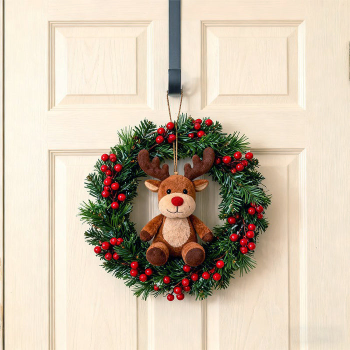 Christmas wreath with a plush reindeer toy hanging on metal hook over a door.