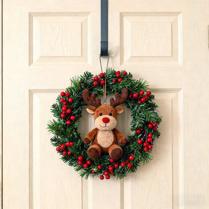 Christmas wreath with a plush reindeer toy hanging on metal hook over a door.