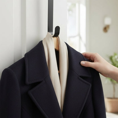 Navy colour coat with a cream scarf on a metal hook with a blurred indoor background