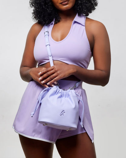 Mini drawstring bucket bag in lavender, styled with a matching athletic outfit for a chic, casual look.