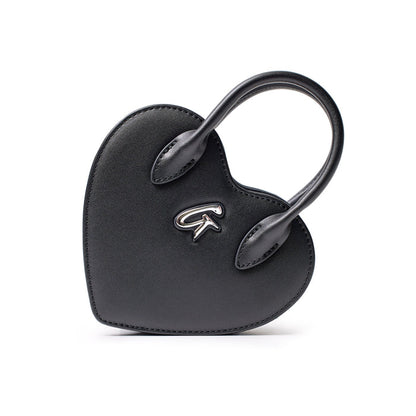 Small black heart-shaped bag with a silver logo, featuring a top handle and sleek, minimalist design.