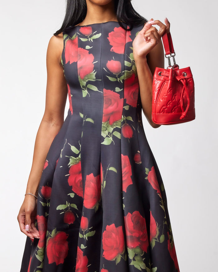 Red mini monogram bucket bag held by a woman in a floral dress, showcasing affordable luxury style.