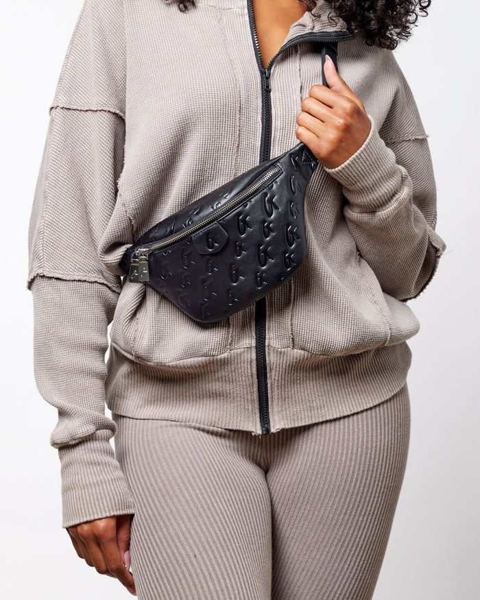 Black mini monogram fanny pack worn across the body, featuring a stylish design and adjustable strap.