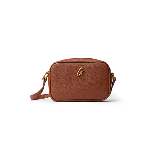 Brown mini pebble camera bag with a gold logo, adjustable strap, and textured leather finish.