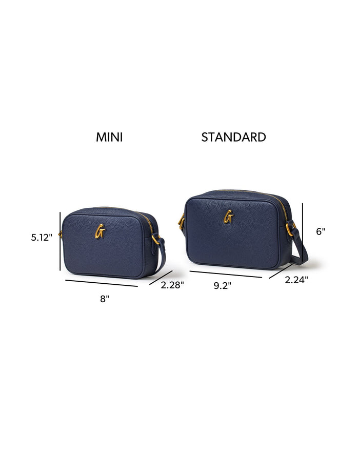 Navy mini pebble camera bag with gold accents, featuring dimensions for mini and standard sizes for comparison.