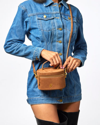 Mini suede vanity bag in brown, stylishly held by a model wearing a denim jacket, showcasing affordable luxury.