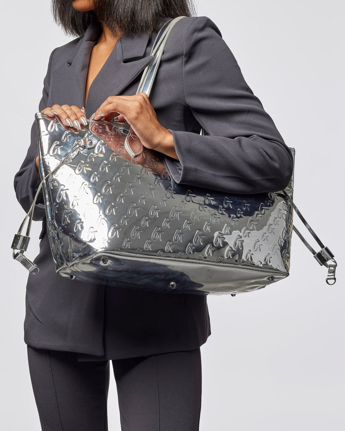 Metallic silver monogram tote bag with wristlet, showcasing a sleek design and stylish functionality for everyday use.