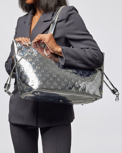 Metallic silver monogram tote bag with wristlet, showcasing a sleek design and stylish functionality for everyday use.
