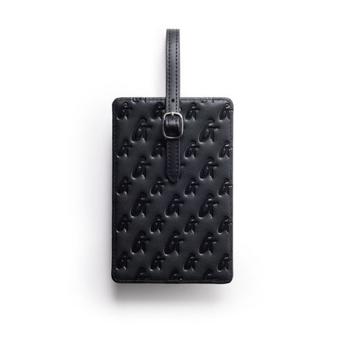 Black monogram luggage tag with embossed logo pattern and adjustable strap for secure attachment.
