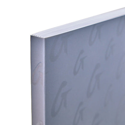 Close-up of a gray monogram notebook with subtle embossed cursive lettering on the cover.