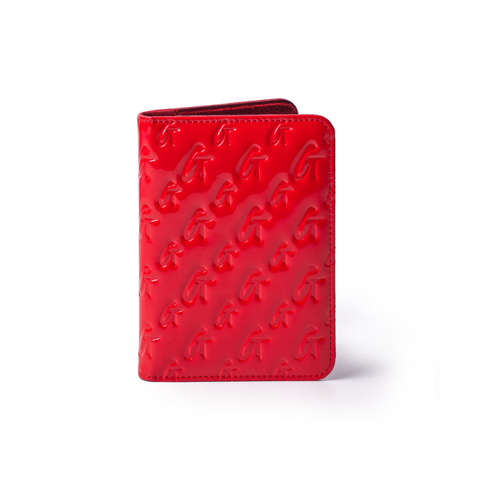 Red mirror finish monogram passport holder with embossed G pattern, compact design for travel accessories.