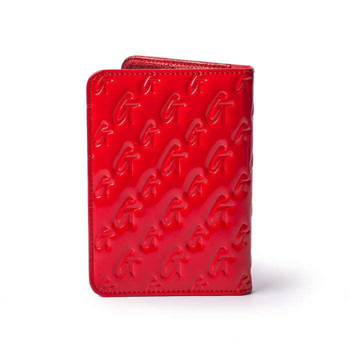 Red mirror finish passport holder with embossed monogram G pattern, designed for stylish travel accessories.