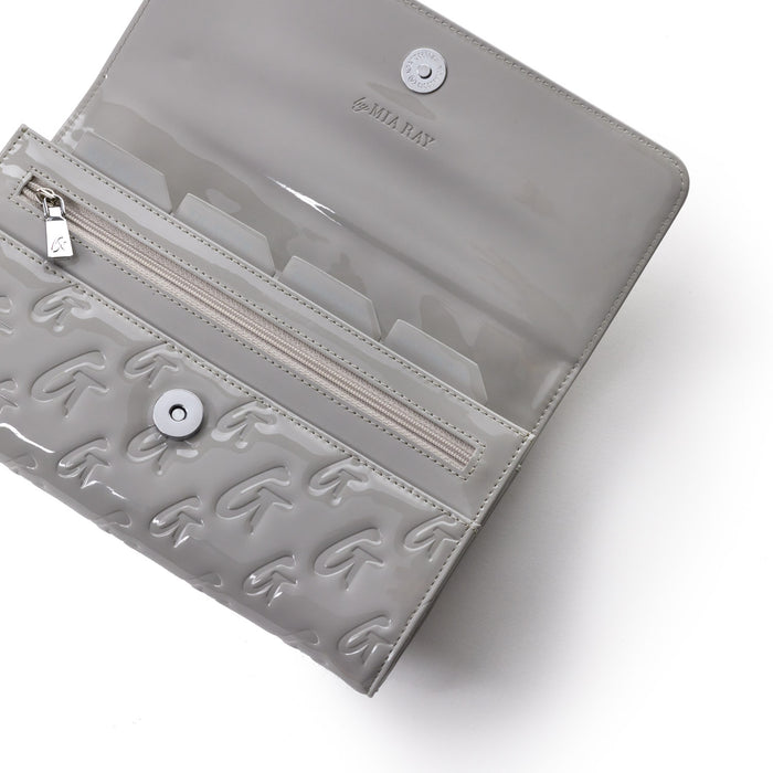 Mirror gray travel wallet with embossed G pattern, clear interior, zip pocket, and snap closure, designed by Mia Ray.