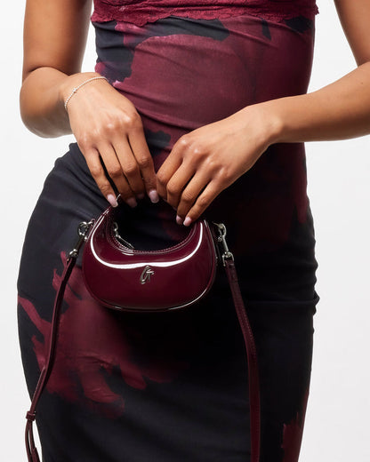 Stylish Nano Mirror Hobo Bag in mirror burgundy, worn crossbody with a sleek design, perfect for chic outings.