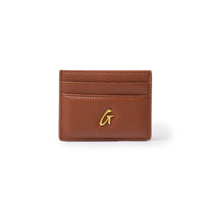 Brown pebble leather card holder with gold "G" logo and three card slots on a white background.