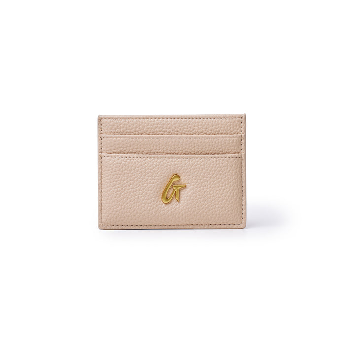 Peach-colored pebble leather card holder with three card slots and a gold "G" logo on the front.