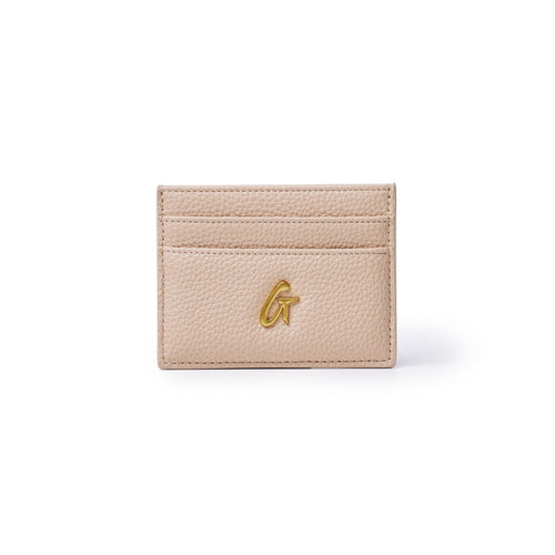 Peach-colored pebble leather card holder with three card slots and a gold "G" logo on the front.