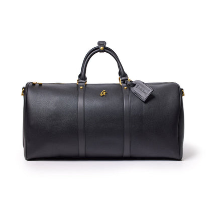 Black Pebble Duffle Bag with leather handles, gold accents, and a luggage tag, designed for travel and storage.