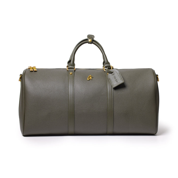 Olive green Pebble duffle bag with leather handles, gold hardware, and a tag, designed for travel and gym use.