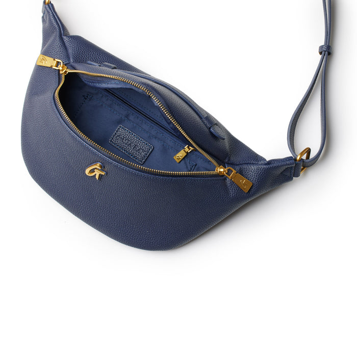 Navy Pebble Fanny Pack with gold zipper and logo, featuring a strap and interior pocket, on a white background.