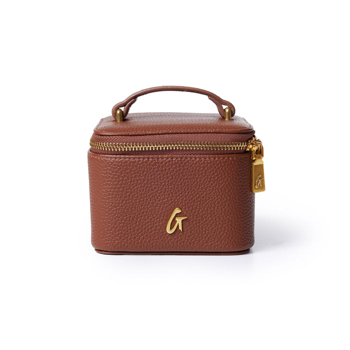 Brown pebble leather jewelry case with gold zipper and handle, featuring a gold "G" logo on the front.