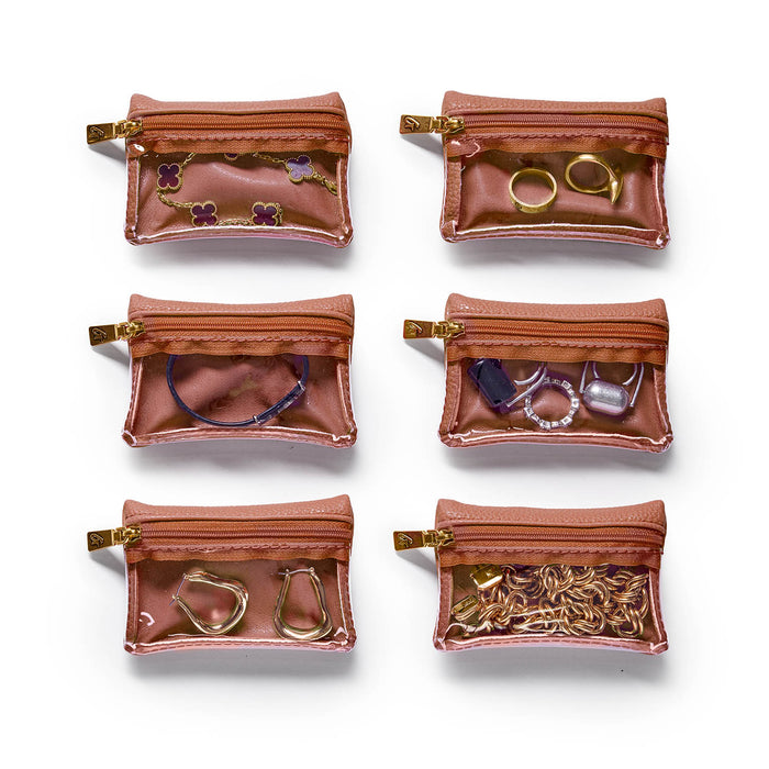 Brown pebble jewelry case with transparent compartments, holding various rings, earrings, and accessories.