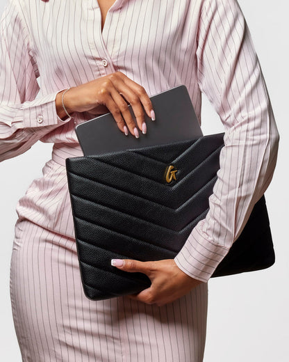 Chic black pebble laptop sleeve with chevron design, elegantly held by a woman in a striped blouse.