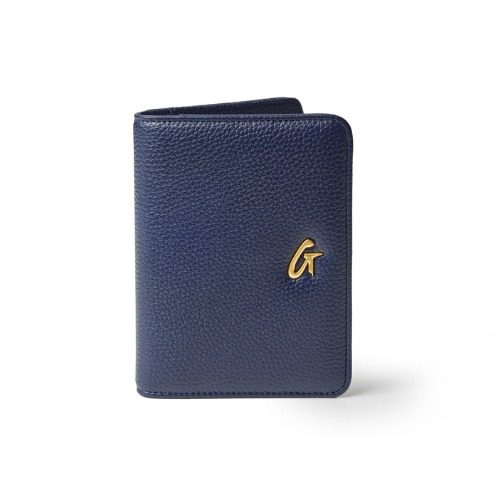Navy Pebble Passport Holder with a gold logo, textured leather, compact design, and rounded edges.