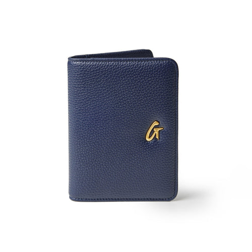 Navy Pebble Passport Holder with a gold logo, textured leather, compact design, and rounded edges.