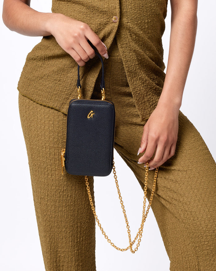Black Pebble Phone Crossbody bag with gold chain and zipper, featuring a small gold logo on textured leather.