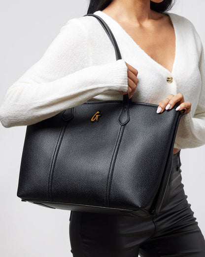Stylish black Pebble Sleek Tote held by a woman, featuring a textured finish and elegant design for everyday use.
