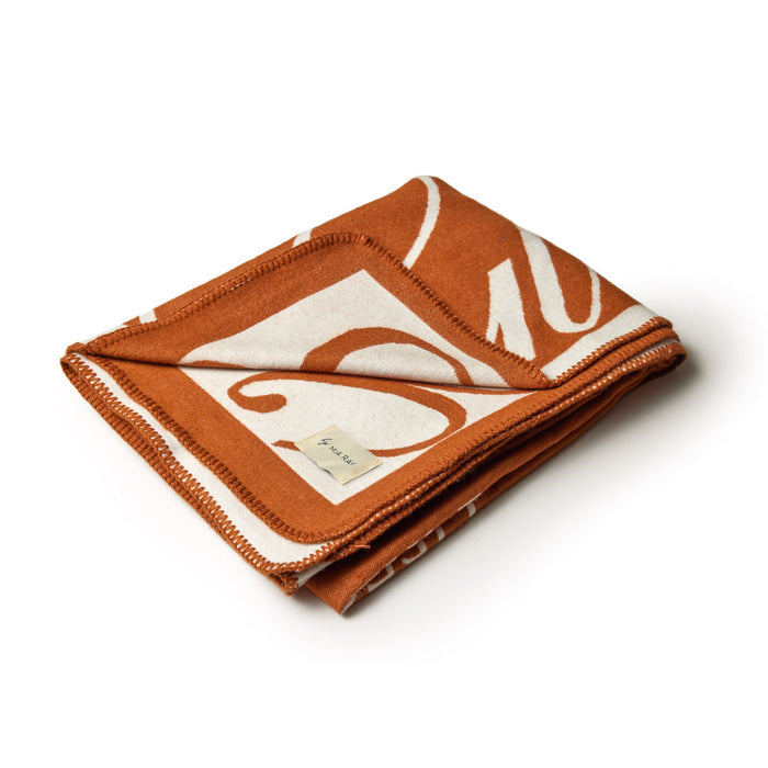 Brown luxury throw blanket with a signature logo design, neatly folded on a white background.